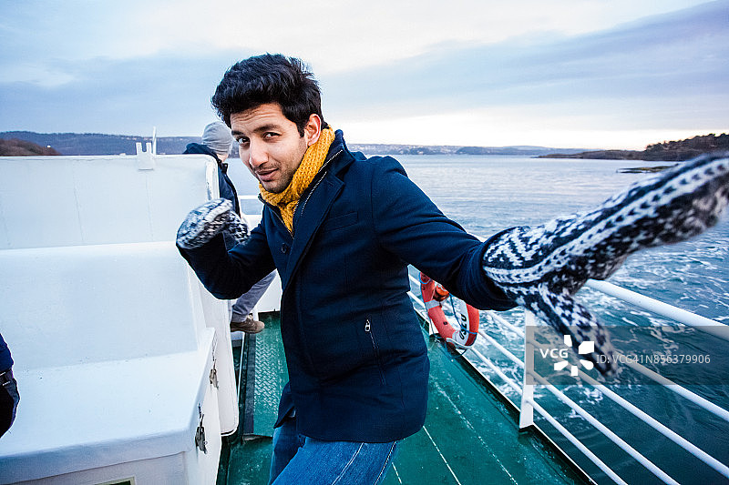 在奥斯陆峡湾冬季渡轮之旅中开玩笑的年轻印度男子图片素材