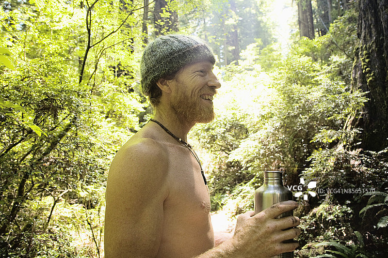 赤膊男人在森林里拿着水壶图片素材