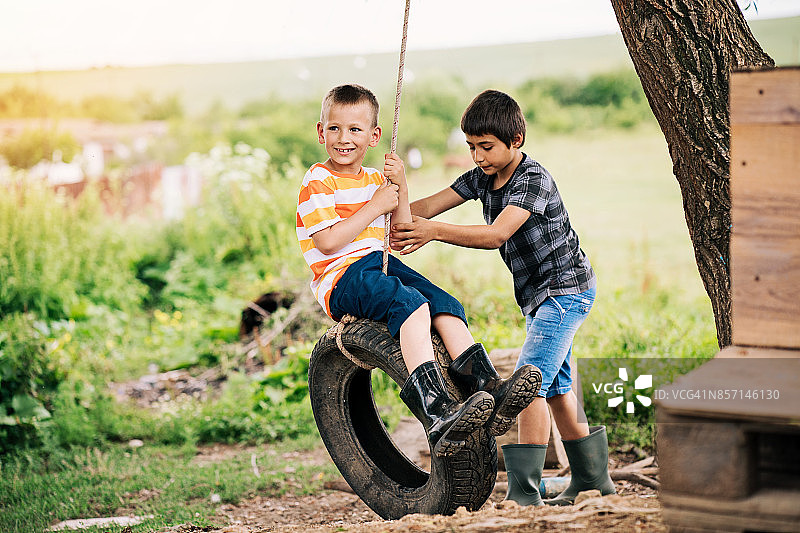 两个男孩玩轮胎秋千图片素材