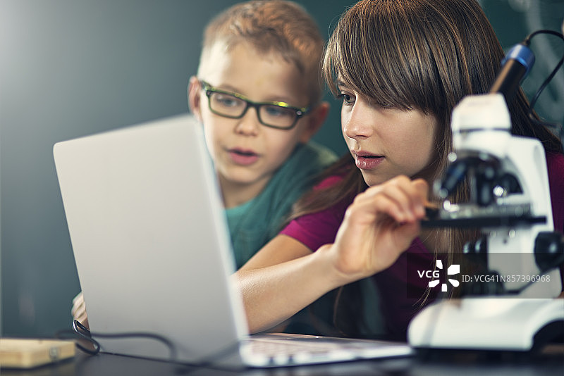 小学生在上生物课时使用显微镜图片素材