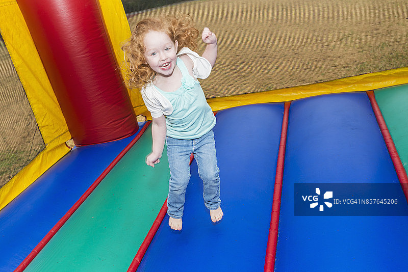 在充气城堡中跳跃的红发小女孩图片素材