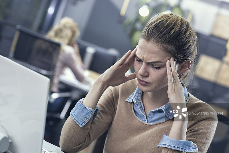 年轻女子在工作中头痛图片素材