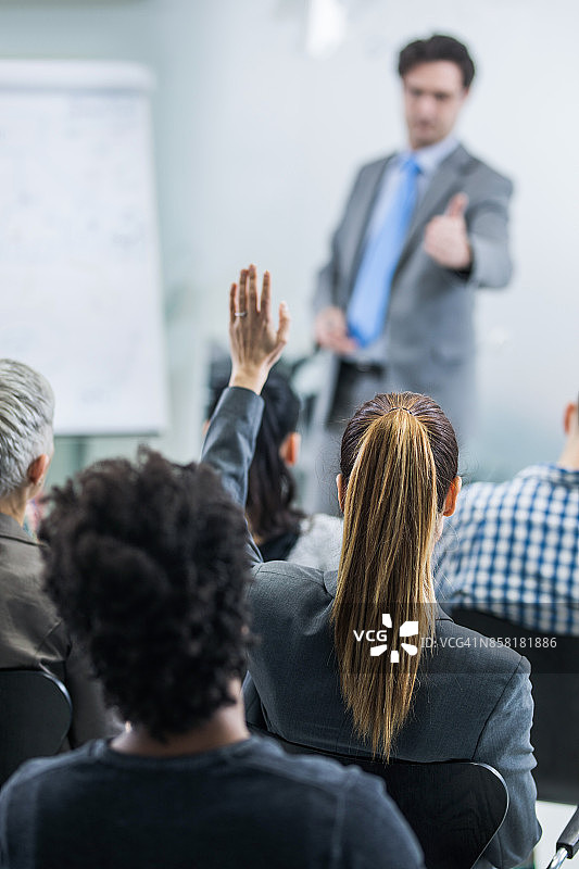 参加商务研讨会举手提问的女子背影图片素材