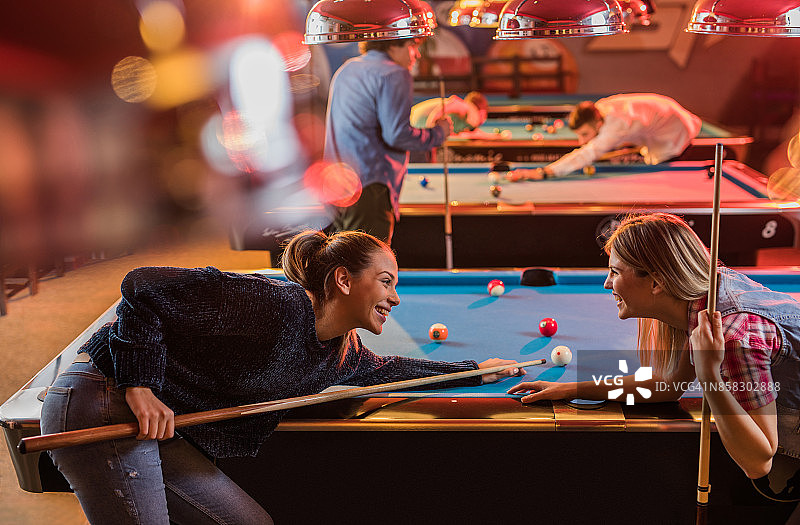 两个快乐的女人在酒吧里玩台球，玩得很开心图片素材