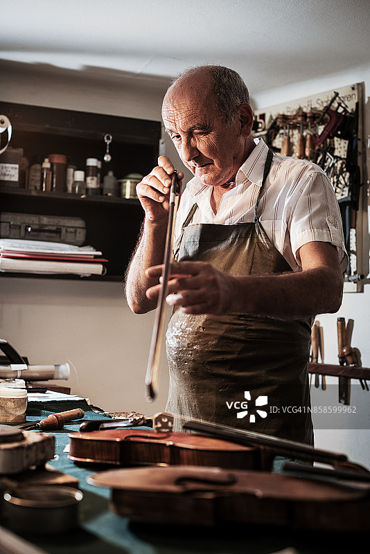 年长工匠检查小提琴琴弦图片素材
