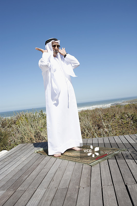 站在木板路上的阿拉伯男子在祈祷图片素材