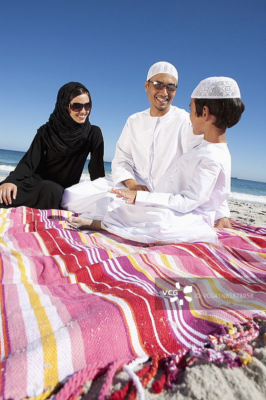 坐在沙滩毯子上的阿拉伯家庭图片素材