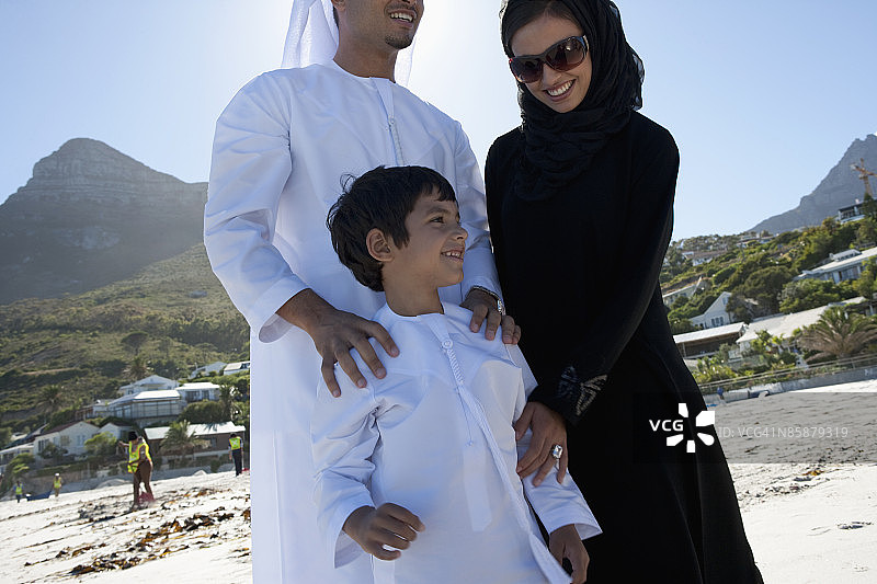 阿拉伯父母和儿子站在海滩上图片素材