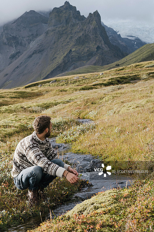 坐在河边欣赏冰川的男人图片素材
