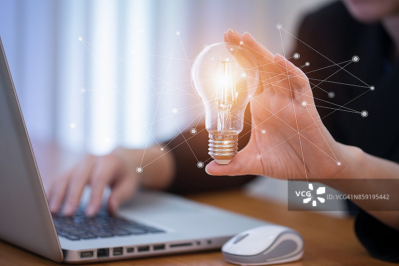 女商人拿着灯泡，象征着创新技术和创意的新想法图片素材