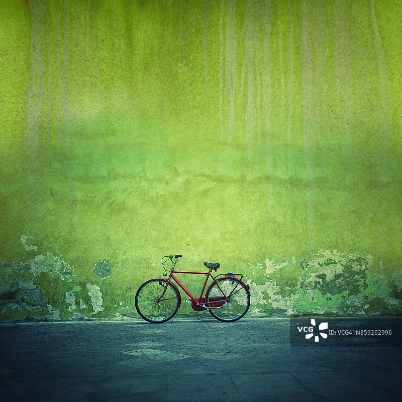 红色复古自行车靠在绿色斑驳的墙壁上图片素材