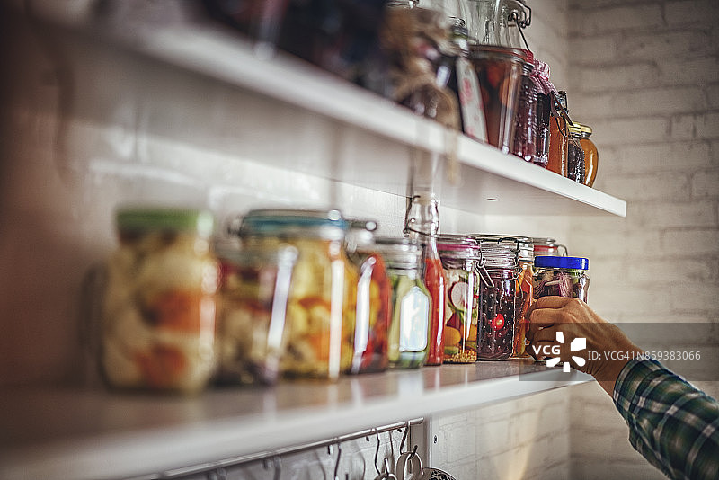 将自制腌制蔬菜放入罐中并放在架子上图片素材