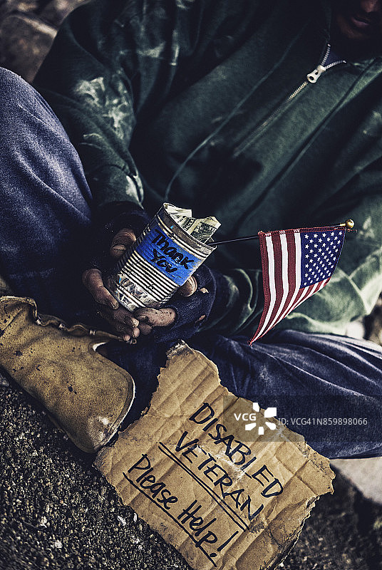 与逆境作斗争：无家可归的残疾退伍军人，带着标牌和钱罐图片素材