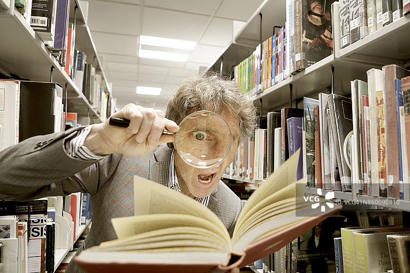 拿着放大镜看书的男人图片素材