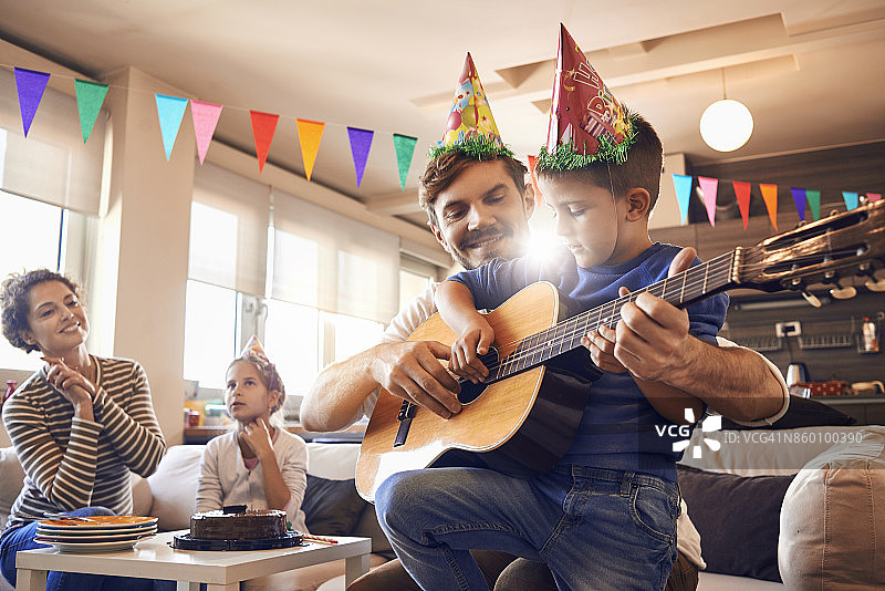 父亲和儿子一起弹吉他庆祝生日图片素材