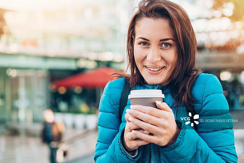 寒冷的一天，微笑的女孩在户外拿着热饮图片素材