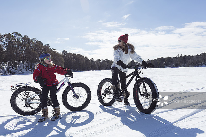 明尼苏达州冬季湖面上骑胖胎自行车的母女图片素材