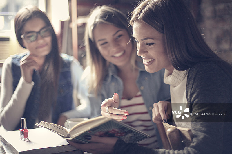 三个年轻学生坐在一起读书，焦点在前台图片素材