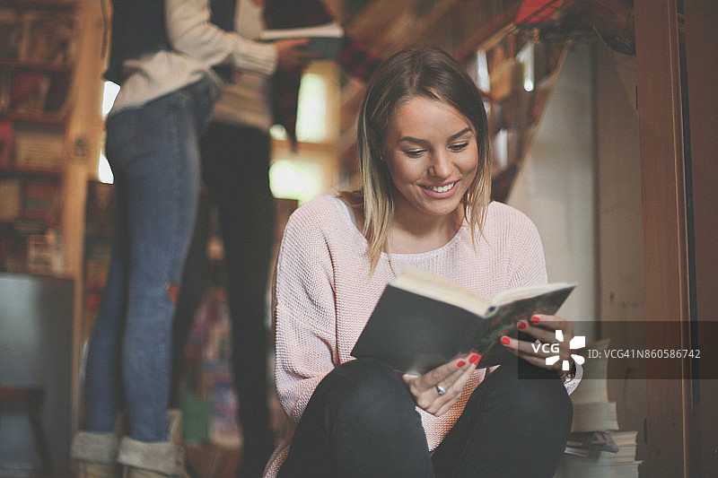 在图书馆看书的快乐年轻女学生图片素材