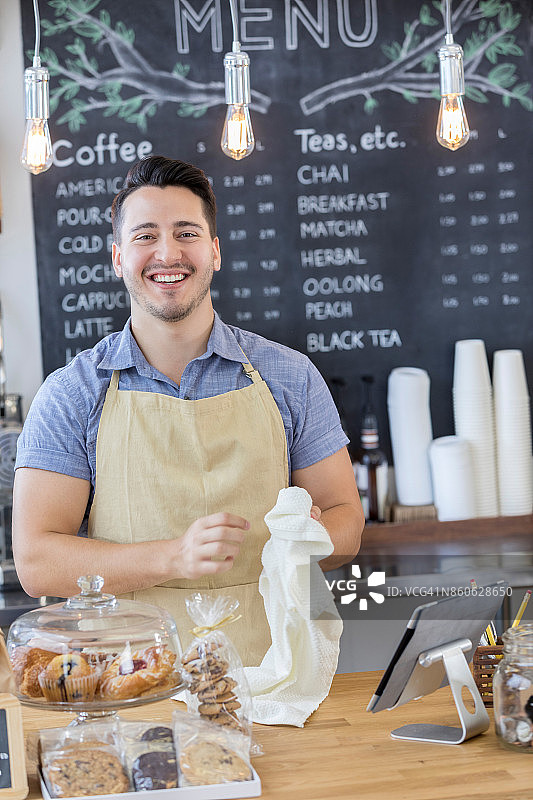 忙碌的新咖啡店老板对着镜头微笑图片素材