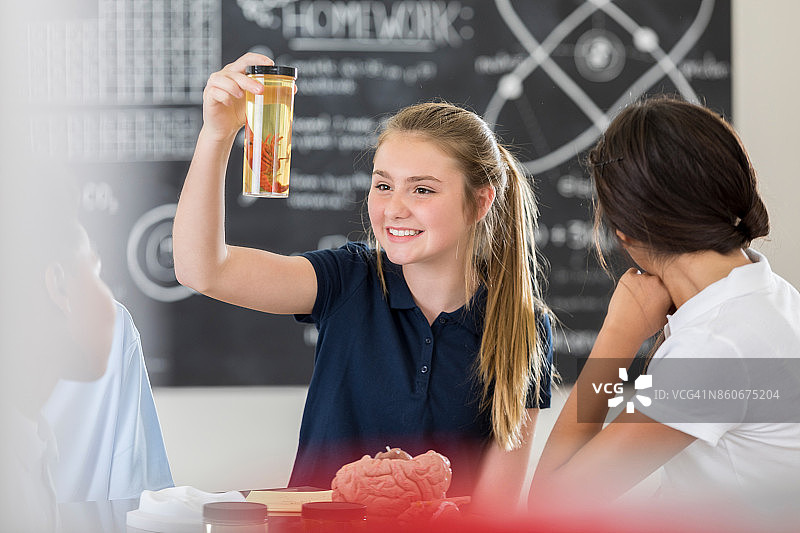 中学女生在玻璃罐里观察小龙虾图片素材