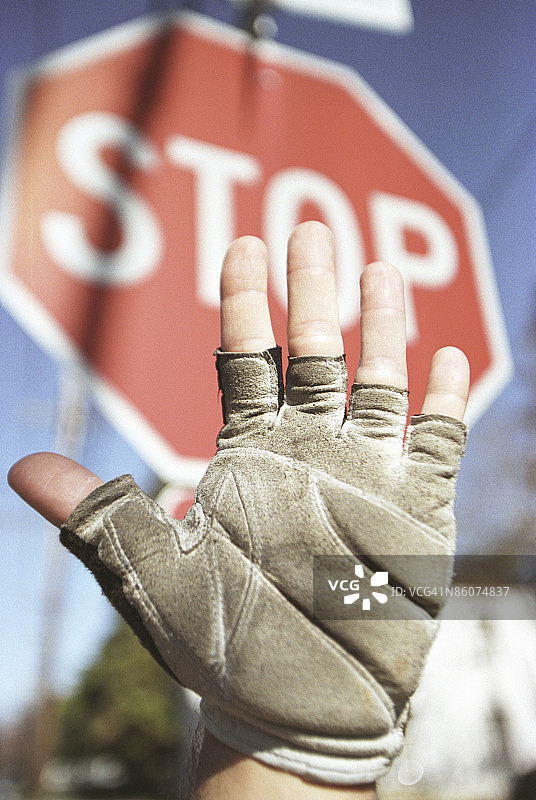 戴手套的手在停止标志旁做手势图片素材