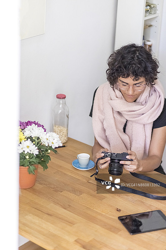 坐在厨房里看相机照片的年轻女人图片素材