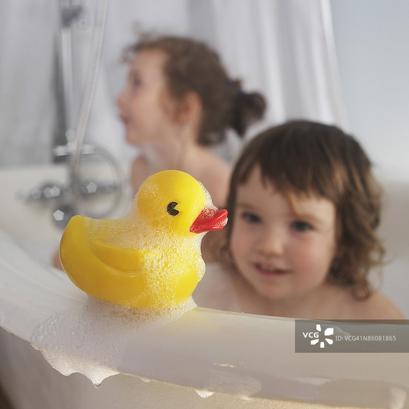 浴缸里儿童旁的橡皮鸭图片素材