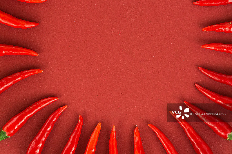 红辣椒，流行的香料概念 - 红色背景上的辣椒半圆静物构图，顶部视图，扁平风格，文本的自由空间图片素材