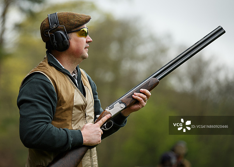 一名男子在飞碟射击时瞄准步枪图片素材