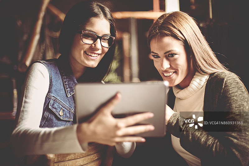 两个年轻女孩在家使用平板电脑图片素材