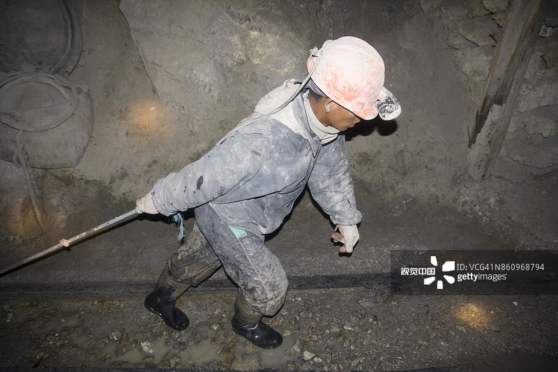 矿工在矿井内拉着一辆装满岩石的矿车图片素材