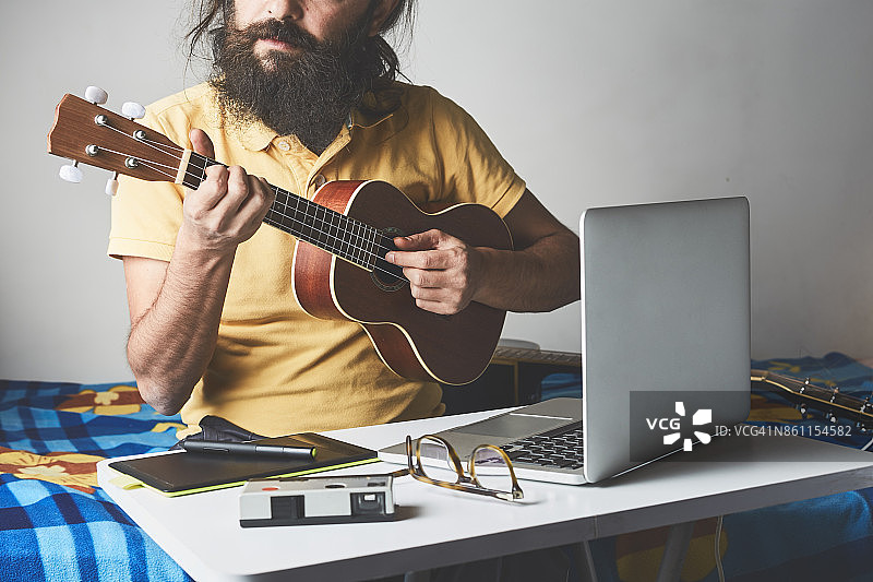 男子在房间里录音并弹奏尤克里里图片素材
