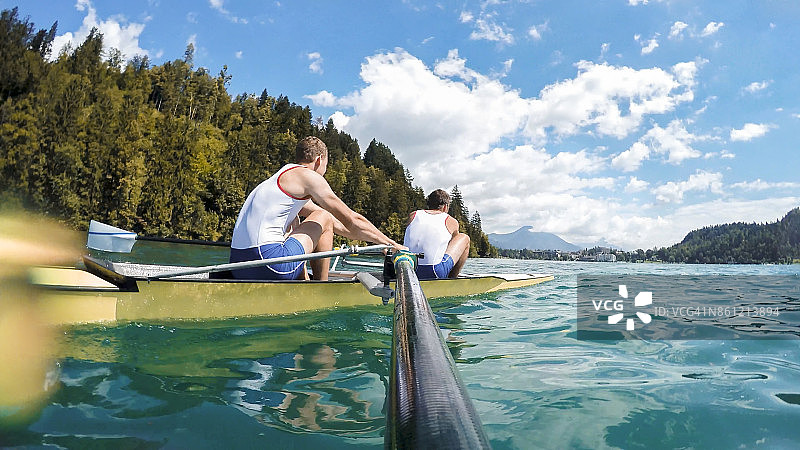 两名男性运动员在傍晚时分划船穿过湖面图片素材