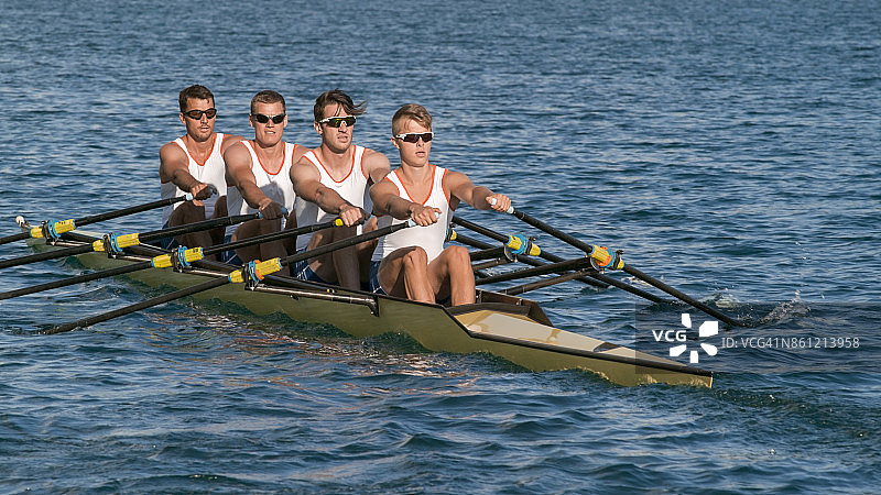四个男运动员在傍晚划船横穿湖面图片素材