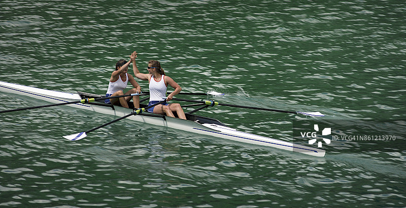 两位女子赛艇运动员在双人划艇上击掌图片素材