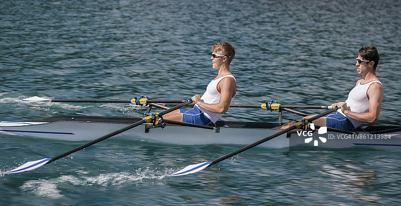 两名男性运动员在傍晚时分划船穿过湖面图片素材