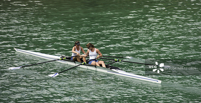 两位女运动员在傍晚时分划过湖面图片素材