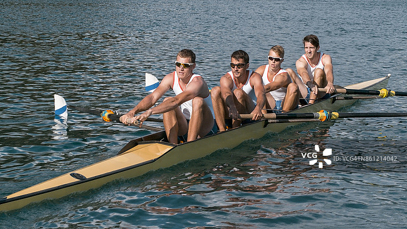 四个男运动员在傍晚划船横穿湖面图片素材