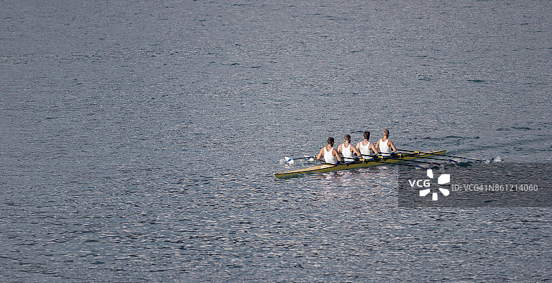 四个男运动员在傍晚划船横穿湖面图片素材