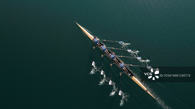 阳光下，四名男运动员在湖上划船图片素材