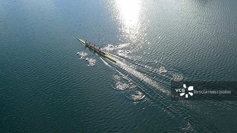 阳光下，四名男运动员在湖上划船图片素材