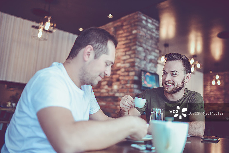 两个微笑的朋友在咖啡馆喝咖啡和社交图片素材