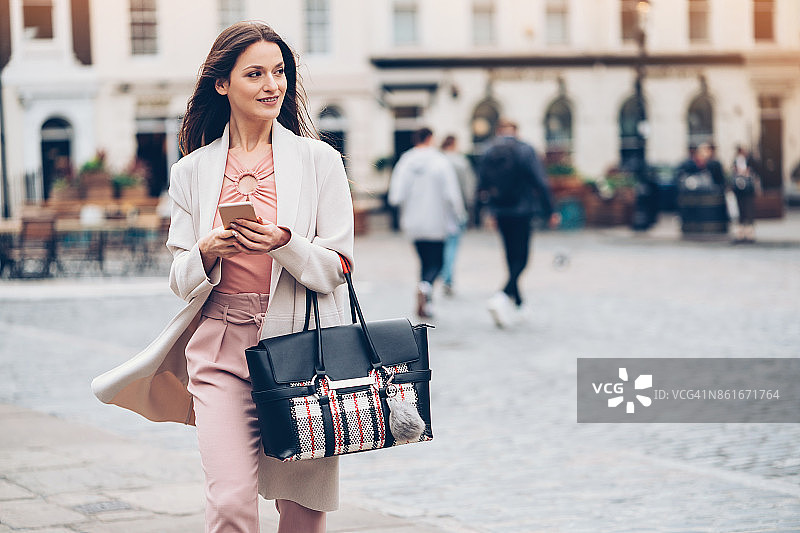在城市户外使用智能手机的优雅女商人图片素材