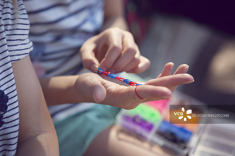孩子们用橡皮筋制作手链。图片素材
