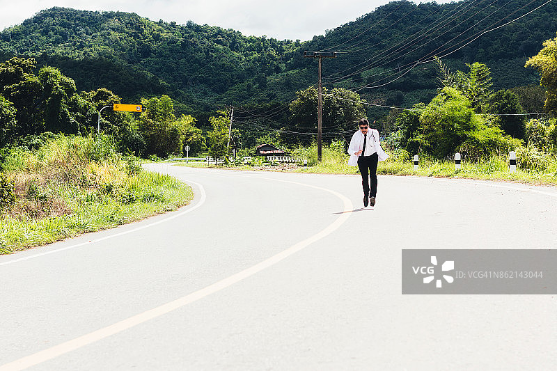 在乡村道路上奔跑的亚洲年轻医生图片素材