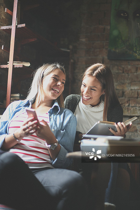 两个女学生在交谈并使用手机图片素材