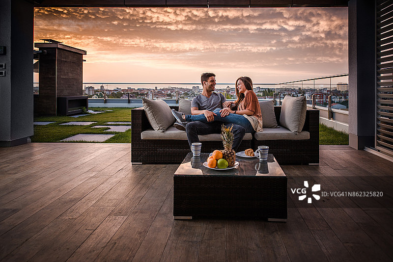 日出时在顶层露台上交流的幸福情侣图片素材