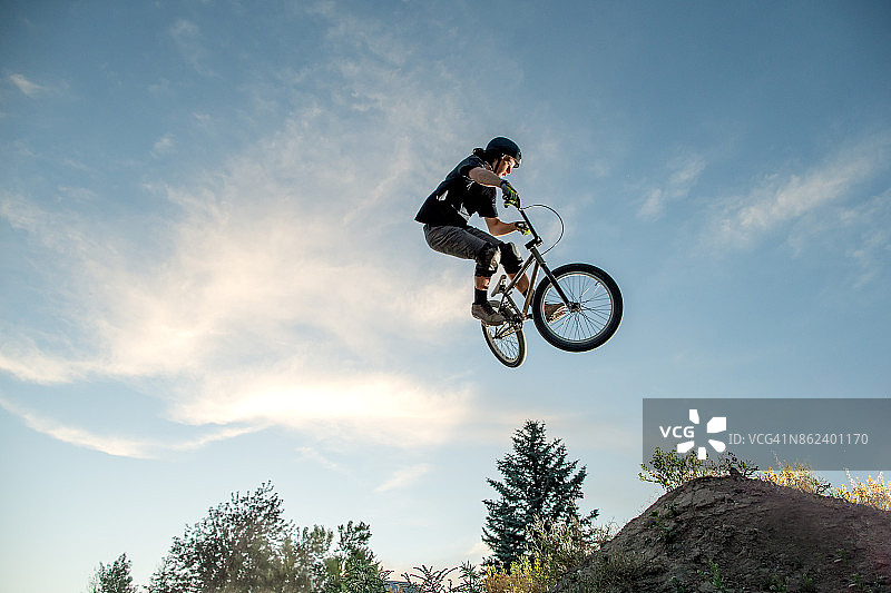 日落时分在蓝天下玩小轮车跳跃的男孩图片素材