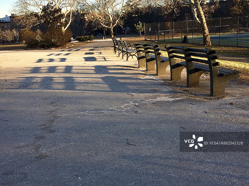 晴朗冬日下午，纽约布鲁克林格林堡公园俯瞰网球场的木凳图片素材